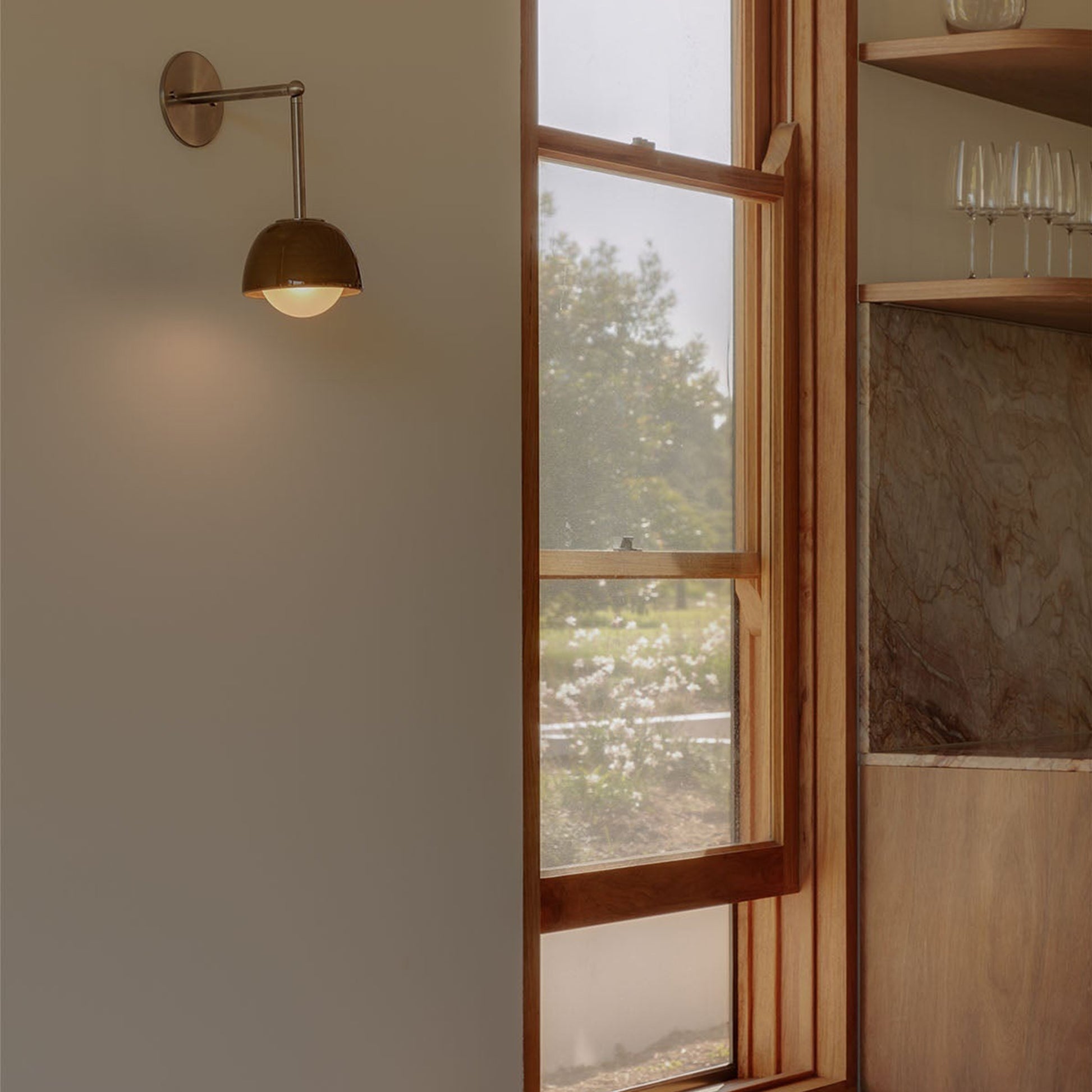 Marz Designs Terra 0 Long Wall Light articulating sconce installed beside a wooden window frame in a warm, modern interior.