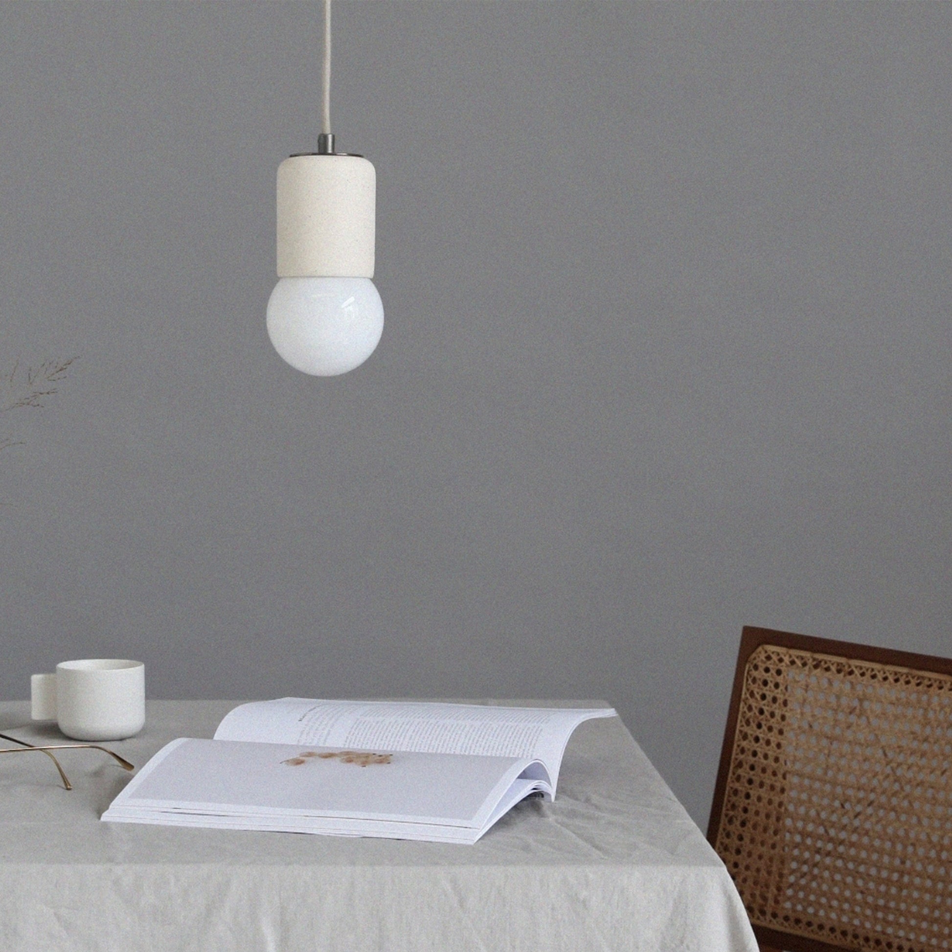 Marz Designs Terra 1 Pendant in vanilla bean ceramic finish, suspended over a minimalist dining table setting.